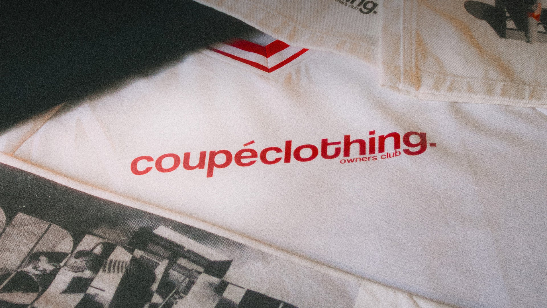White jersey with red 'coupeclothing' logo amongst other clothing items.